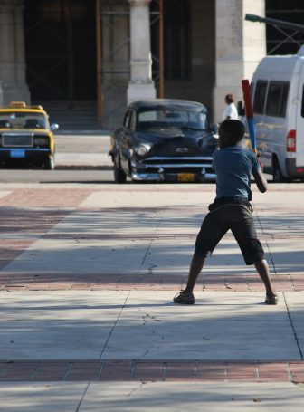 Un ragazzino gioca a baseball nel centro di Avana