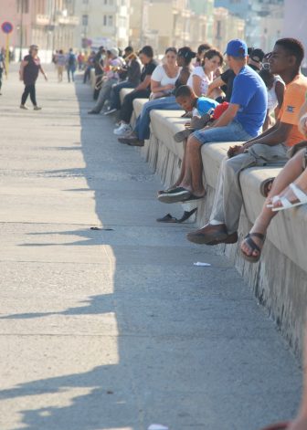 many people sitting on the wall along Malecon