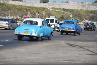 two blue classic cars running on the road in Havana