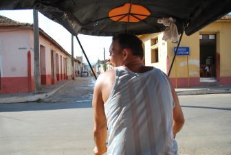 the back of the driver of a bicycle taxi running on the road in Trinidad in Cuba