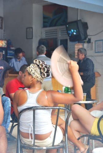 a woman cooling herself with a fan at a cafe in Trinidad, Cuba