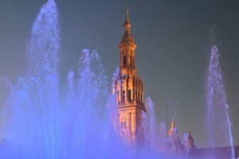 the lit up fountain and a tower at Plaza de España in Seville