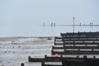 引き潮のウィッツタブルの海辺を歩く人々