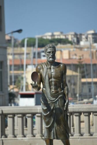 the statue of Archimedes standing between Ortigia and mainland Sicily