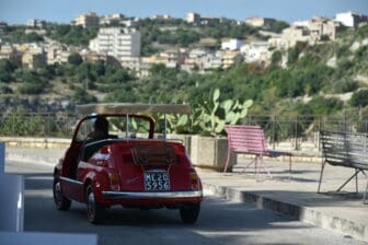 the red Cinquecento passing the view point in Modica, Sicily