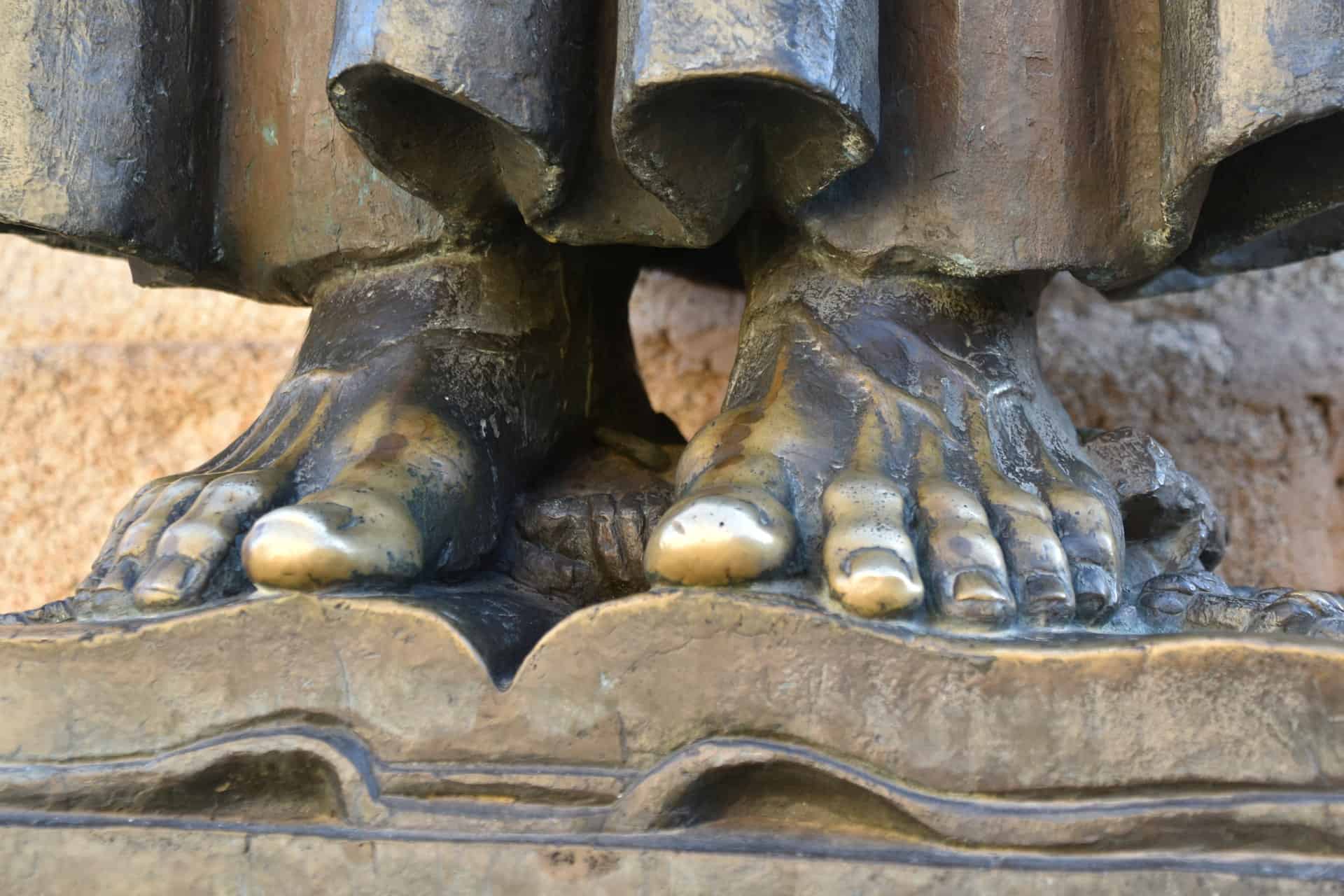 feet of the statue of Torre de Bujaco standing outside of the cathedral in Caceres, Spain