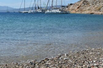 Yachts are anchored offshore on Mandraki Beach on Hydra island, Greece