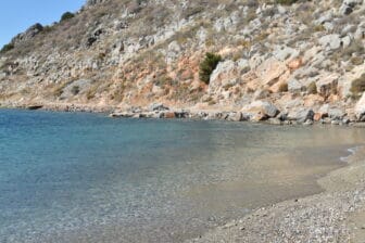 the clean water of Mandraki Beach on Hydra island in Greece