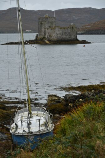 Kisimul Castle and an abandoned boat on Barra Island in Hebrides, Scotland 