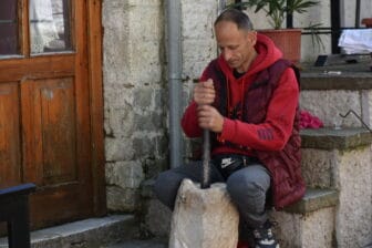 a man pounding the coffee beans in the stone mill during the demonstration of coffee making in Gjirokaster, Albania