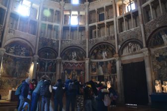 イタリア、パルマの大聖堂のバプティストリー内で説明を聞く社会科見学の子供たち