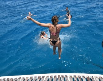 ギリシャのクレタ島沖のスピナロンガ島への観光船から海に飛び込む人